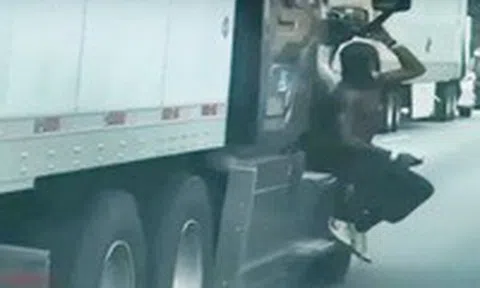 Người đàn ông cởi trần, bám ngoài cửa xe tải đang chạy trên xa lộicon