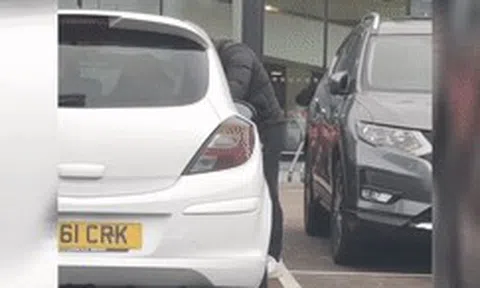 Người đàn ông đứng cạnh chiếc xe với hành động dễ gây hiểu lầmicon