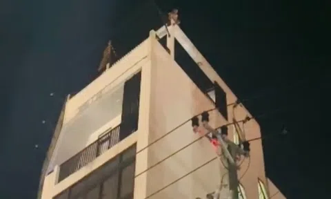 Một người có biểu hiện mất kiểm soát ngồi trên nóc tòa nhà 4 tầng